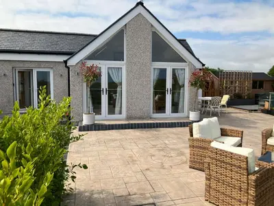 a patio with chairs and tables in front of a house at Cherry Tree Cottage in Stranraer
