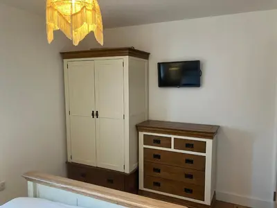 a bedroom with a cabinet and a tv on the wall at Cherry Tree Cottage in Stranraer