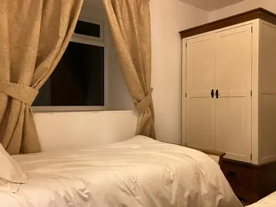 a bedroom with a bed and a cabinet and a window at Cherry Tree Cottage in Stranraer