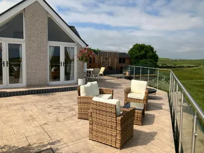 a patio with wicker chairs and a table at Cherry Tree Cottage in Stranraer
