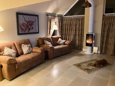 a living room with two couches and a dog laying on the floor at Cherry Tree Cottage in Stranraer