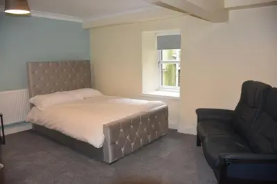 a bedroom with a bed and a couch and a window at The Blue House holiday home in Egremont