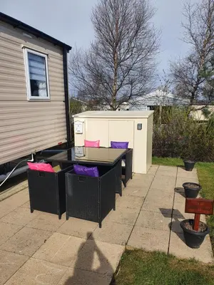 a ping pong table in a yard next to a house at 3 bedroom Caravan Craigtara in Ayr