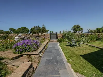 a garden with a stone pathway and purple flowers at How Hill Farm Cottage in Penrith