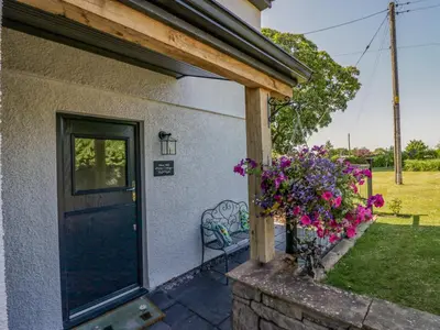 a door of a house with a bench and flowers at How Hill Farm Cottage in Penrith