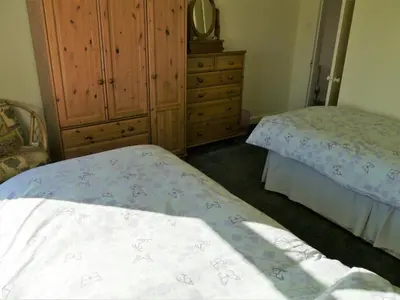 a bedroom with two beds and a dresser at Woodhall Cottage in Annan