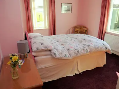 a bedroom with a bed and a table with flowers on it at Woodhall Cottage in Annan