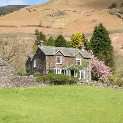 a large stone house in a field of grass at Bramrigg House in Grasmere