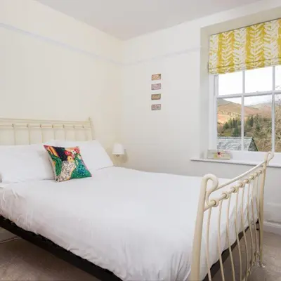 a white bed in a white bedroom with a window at Bramrigg House in Grasmere