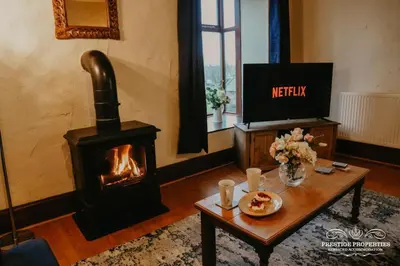 a living room with a wood stove and a table at Pine lodge by Prestige Properties SA in Seascale
