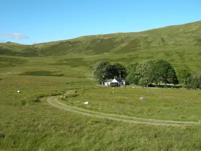 a field with a barn in the middle of a hill at Riverside House in Thornhill