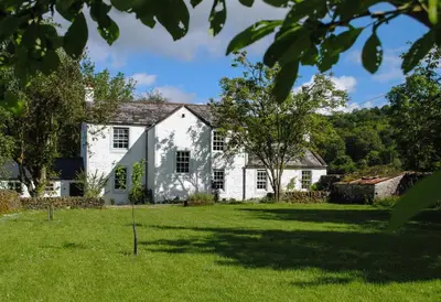 an exterior view of a white house with a yard at Riverside House in Thornhill