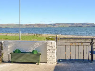 a green bench with two balls on it near the water at Ailsa Craig View in Stranraer