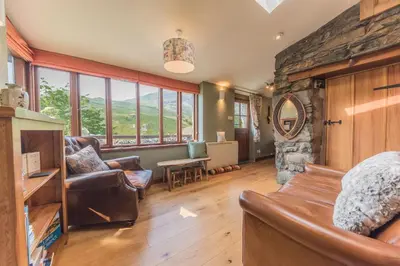 a living room with a couch and a stone fireplace at Slater Bob's Coppermines Valley in Coniston