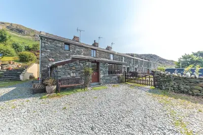 a stone house with two benches in front of it at Slater Bob's Coppermines Valley in Coniston