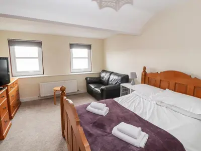 a bedroom with a bed and a couch and a television at Cobbleken in Cockermouth