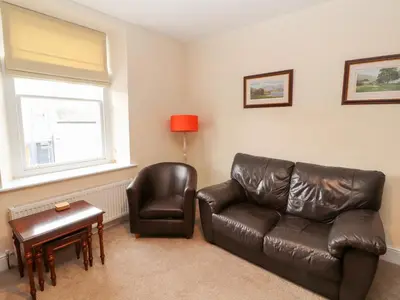a living room with a leather couch and a chair at Cobbleken in Cockermouth