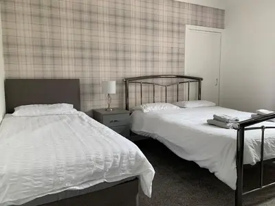 a bedroom with two beds and a table with a lamp at 10 Burns Street, Tarbolton KA5 5RA in Tarbolton
