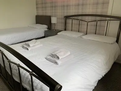 two beds in a bedroom with towels on them at 10 Burns Street, Tarbolton KA5 5RA in Tarbolton