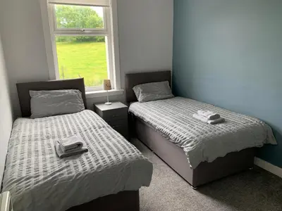two twin beds in a room with a window at 10 Burns Street, Tarbolton KA5 5RA in Tarbolton