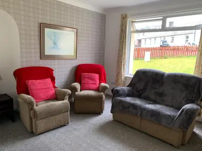 a living room with two chairs and a couch at 10 Burns Street, Tarbolton KA5 5RA in Tarbolton