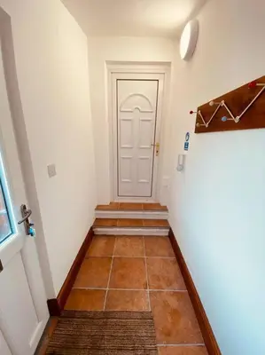 a hallway with a white door and a tile floor at Luxury 2 bed apt 4 mins from M6 J44 pet friendly, in Carlisle