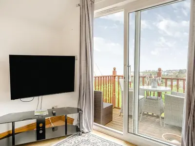 a living room with a flat screen tv and a balcony at Ben Ma Cree in Portpatrick