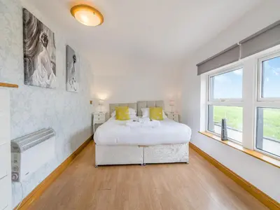 a white bedroom with a bed and a window at Ben Ma Cree in Portpatrick
