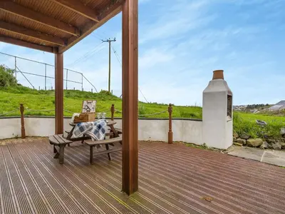 a wooden porch with a bench on a deck at Ben Ma Cree in Portpatrick