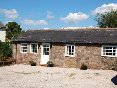 a small brick building with white windows and plants at Sycamore Cottage in Ellonby