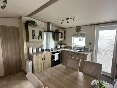 a kitchen with a wooden table and a dining room at Luxury Lake District Holiday Lodge-Sleeps 4 in Cockermouth