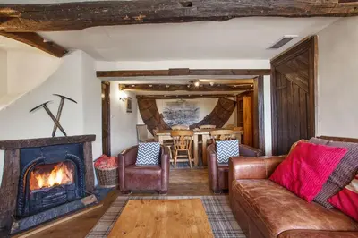 a living room with a couch and a fireplace at The Coppermines Mountain Cottages Sawyers, Carpenters, Millrace, Pelton Wheel, Sleeps 22 in Coniston