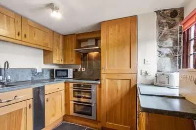 a kitchen with wooden cabinets and a stove top oven at The Coppermines Mountain Cottages Sawyers, Carpenters, Millrace, Pelton Wheel, Sleeps 22 in Coniston