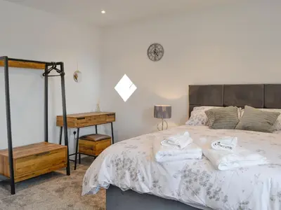 a bedroom with a bed and a clock on the wall at Old Byre Cottage - Uk43377 in Kirklinton