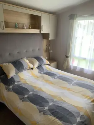 a bedroom with a bed with a comforter and a window at Grasmere Lodge Unit 31 in Carlisle