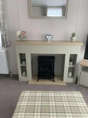 a living room with a fireplace and a mirror at Grasmere Lodge Unit 31 in Carlisle