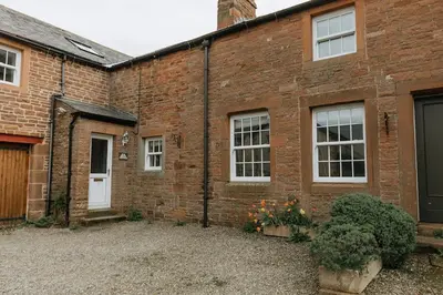 a brick building with a door and a courtyard at ELM HOUSE BARN - Converted One Bed Barn at the gateway to the Lake District National Park in High Hesket