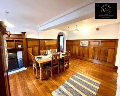 a dining room with a table and wooden cabinets at Three Bedroom in Seascale