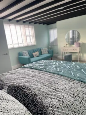 a bedroom with a bed and a blue couch at Hollie's Beach House in Peel