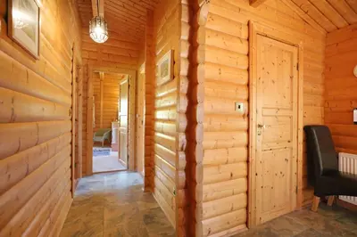 a hallway of a wooden cabin with a door and a chair at Birchlea in Kippford