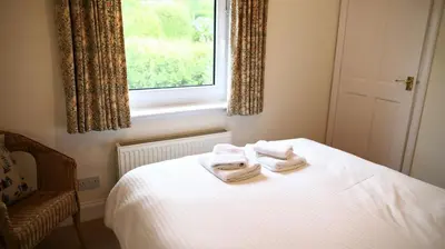 a bedroom with two towels on a bed with a window at The Bridge in Kippford