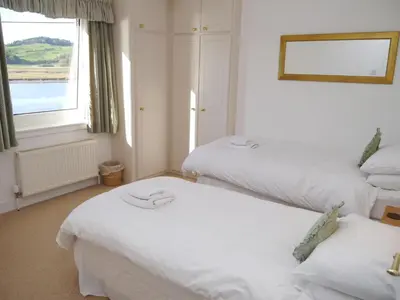two beds in a room with a window at The Bridge in Kippford