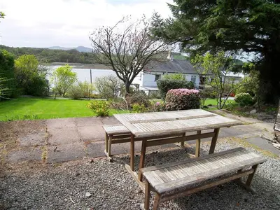 a wooden picnic table and bench in a yard at The Bridge in Kippford