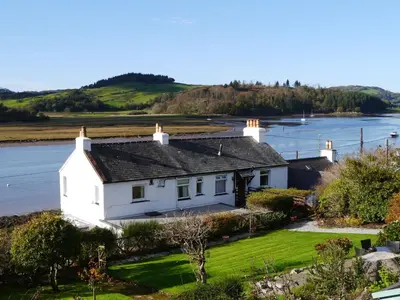 an aerial view of a white house next to the water at The Bridge in Kippford