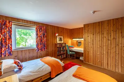 a bedroom with two beds and a window and a desk at Bells View in Kippford