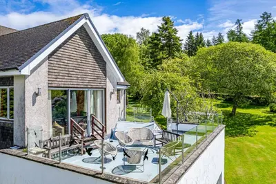 a patio with a table and chairs on a balcony at Bells View in Kippford