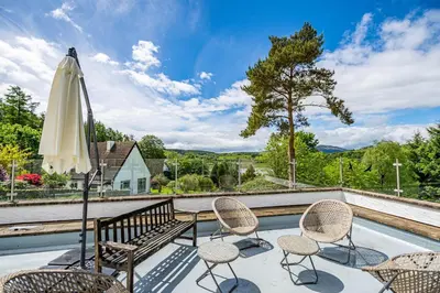 a patio with a bench and chairs and a umbrella at Bells View in Kippford