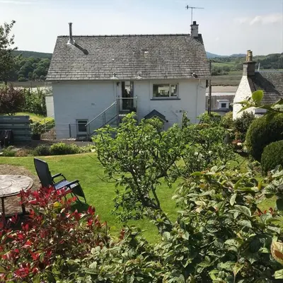 a white house with a table and chairs in a yard at Phoenix Cottage in Kippford