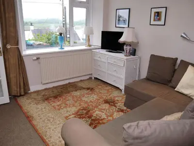 a living room with a couch and a tv and a window at Phoenix Cottage in Kippford