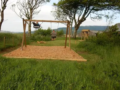 a man sitting on a swing in a field at Barnacle in Mainsriddle